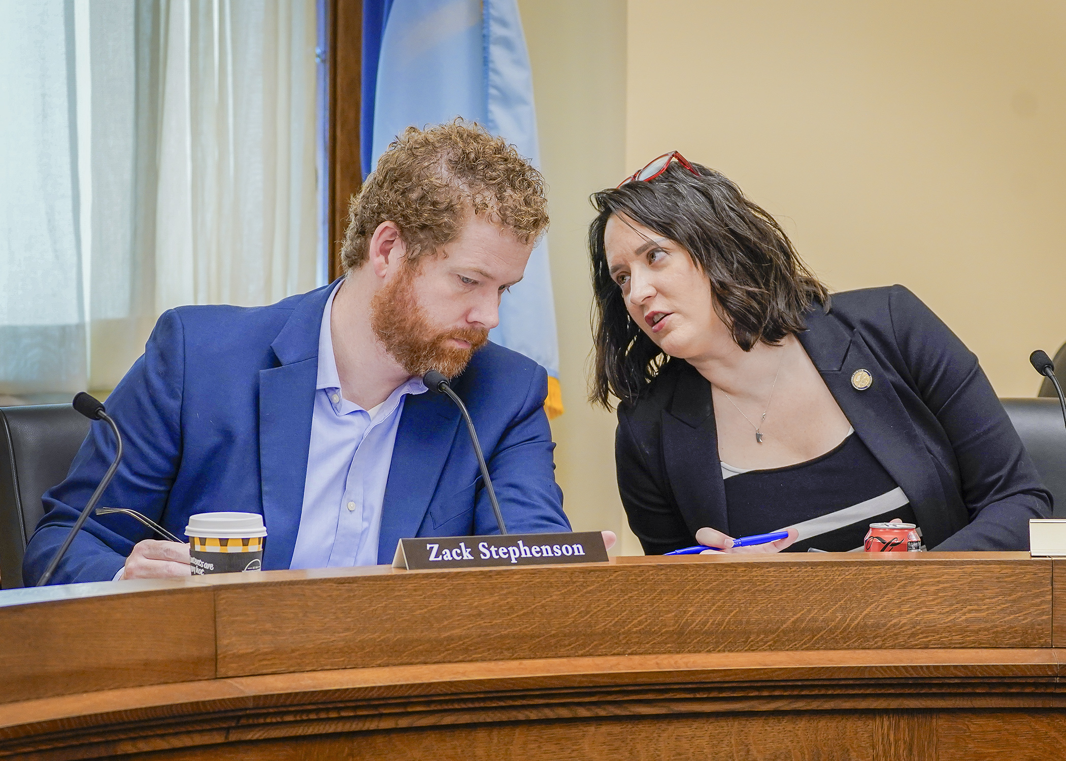 Rep. Zack Stephenson and Sen. Lindsey Port confer May 15 prior to gaveling in the conference committee on the cannabis policy bill. (Photo by Andrew VonBank)